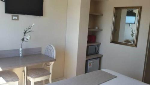 Habitación pequeña con mesa y espejo. en Hotel Aranjuez, en Chillán