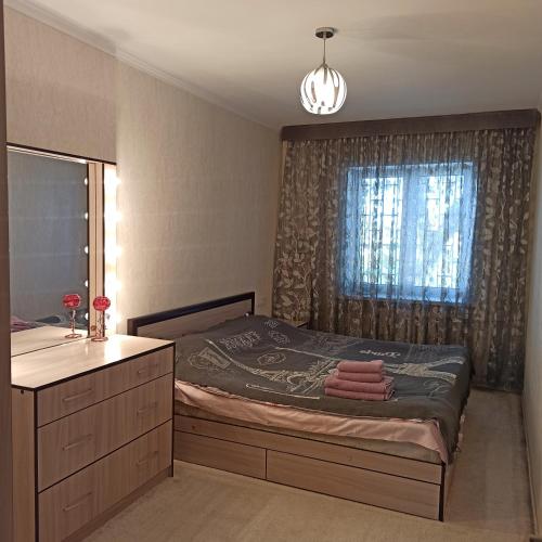 una camera con letto, lavandino e finestra di Комфортно и уютно a Bishkek