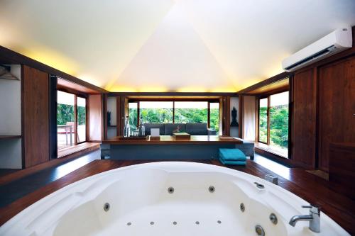 a large white bath tub in a room with windows at The Dune Eco Village and Spa - Pondicherry in Pondicherry