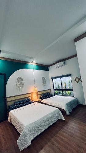 Victoria Homestay في Phường Sáu: سريرين في غرفة نوم مع جدران خضراء