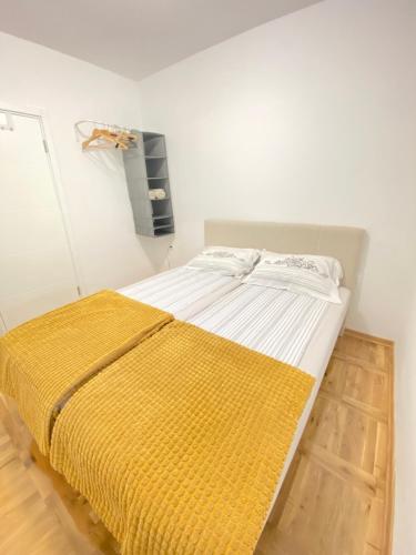 a bed in a white room with a yellow blanket at The Sailor in Belgrade