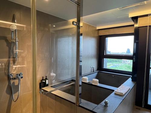 a bathroom with a shower and a sink and a window at Sunrise Hot Spring House in Toucheng