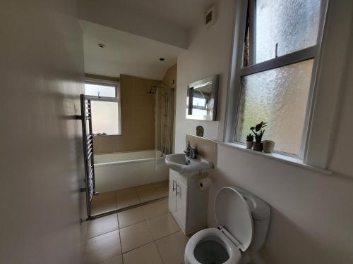 een badkamer met een toilet, een wastafel en een raam bij Remarkable 1-Bed House the entire first floor in Westcliff On Sea