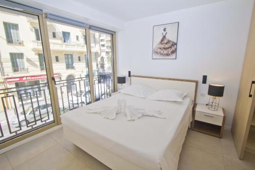 une chambre avec un lit blanc et une grande fenêtre dans l'établissement Sea Front Palace Promenade, à Nice