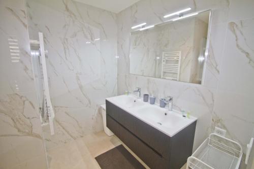 une salle de bain blanche avec un lavabo et un miroir dans l'établissement Sea Front Palace Promenade, à Nice