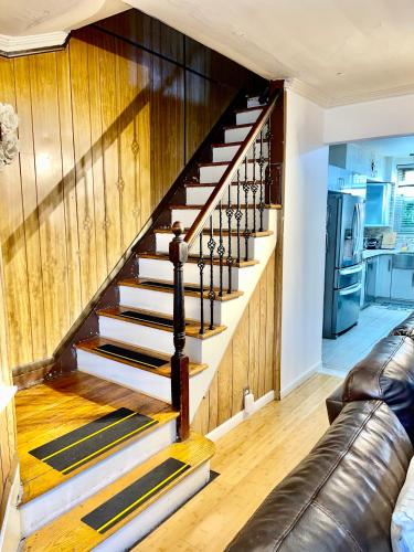 a spiral staircase in a living room with a leather couch at LGA airport 3 mins, 3 BR Duplex House, Parking and private backyard, 9mins subway! in East Elmhurst