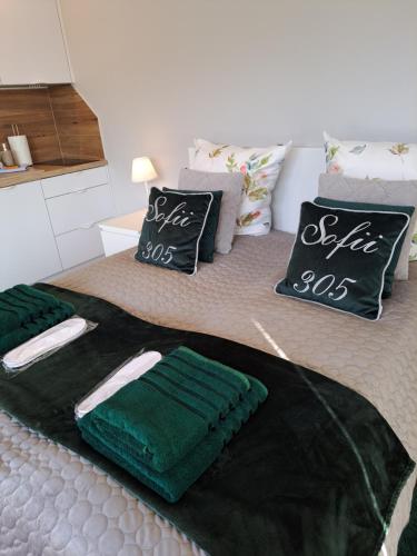 1 dormitorio con 2 camas con mantas y almohadas verdes en Rubus 305 Sofii en Świnoujście