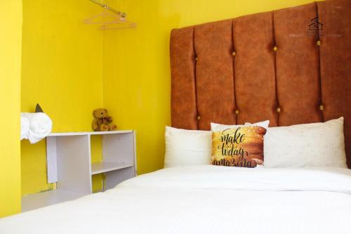 a bedroom with a bed and a yellow wall at HN airbnb in Nairobi