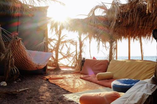 a living room with a couch and hammocks on the beach at Fully equipped Remote off-grid Solar Wooden Home in Dahab