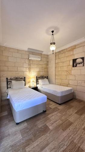 two beds in a large room with a wall at Mardin Konak Osmanlı in Mardin