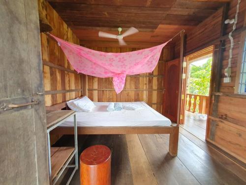 Ce lit se trouve dans une chambre en bois dotée d'une moustiquaire rose. dans l'établissement Banlung Mountain View Treks & Tours, à Banlung