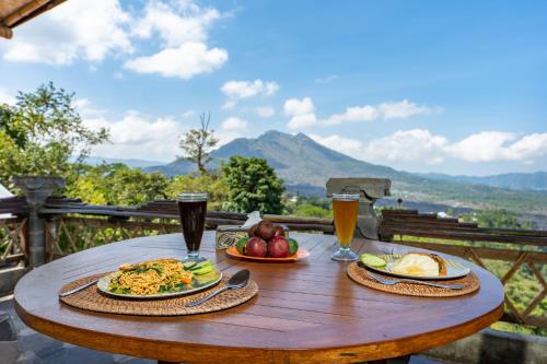 a wooden table with two plates of food and two glasses of beer at Tiing Bali Guest House Kintamani in Kintamani