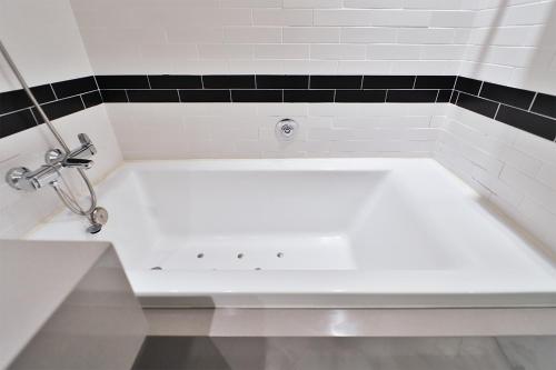 a white bath tub in a bathroom with black tiles at Brown Dot Hotel Ulsan Samsan in Ulsan