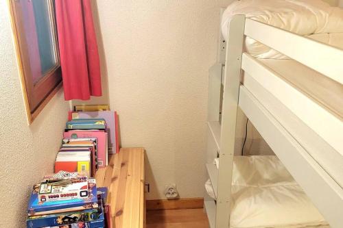 une pile de livres sur une étagère à côté d'un lit superposé dans l'établissement Duplex 4/6p Le Familial, à Laveissière