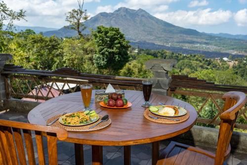 a wooden table with two plates of food and drinks at Tiing Bali Guest House Kintamani in Kintamani