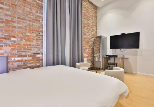 a bedroom with a white bed and a brick wall at Brown Dot Hotel Ulsan Samsan in Ulsan