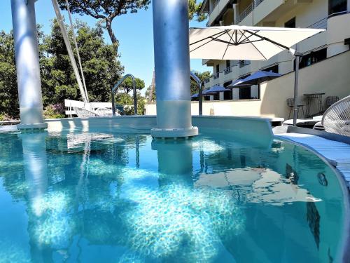 uma piscina com um guarda-sol num edifício em Hotel Acapulco em Forte dei Marmi