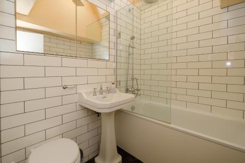 a bathroom with a sink and a toilet and a tub at Hill House Apartment in Framlingham