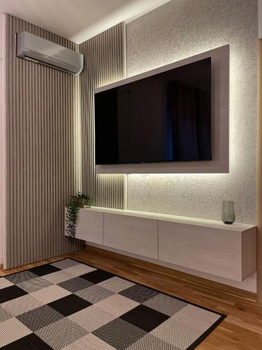 a living room with a television on a wall at Fly apartments in Ledine