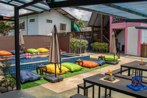 a pool with colorful pillows and tables and an umbrella at K-Bunk Hostel Pai Walking Street in Pai