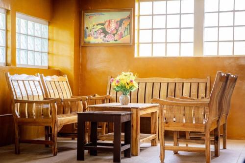 a dining room with wooden chairs and a table with flowers on it at Orchid Pool Villa Phuket - SHA Extra Plus in Phuket Town