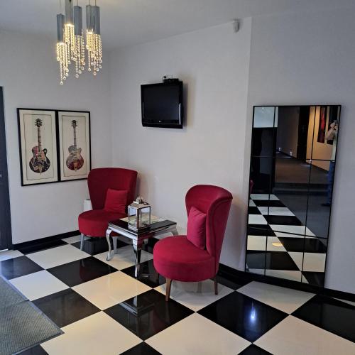 a room with two red chairs and a table and a television at Piano in Nowy Sącz