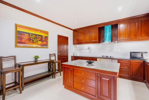 a kitchen with wooden cabinets and a table at Orchid Pool Villa Phuket - SHA Extra Plus in Phuket Town
