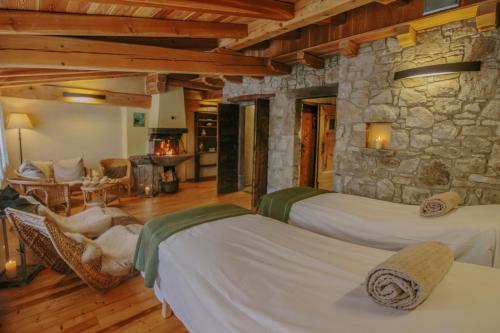 a bedroom with two beds and a stone wall at Agriturismo Ferdy in Lenna