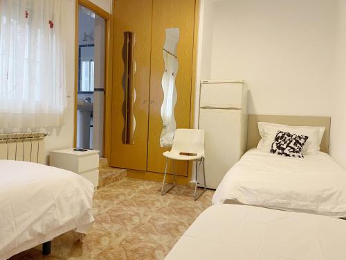 a room with two beds and a chair in it at Pensión el Carmen in Alcobendas