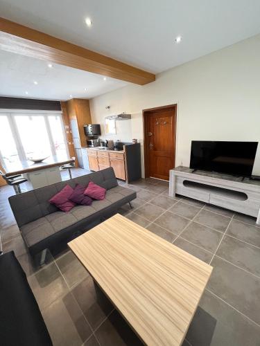 a living room with a couch and a flat screen tv at la petite maisonnette in Le Plessis-Feu-Aussoux