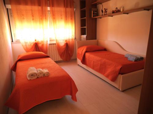 2 camas en una habitación pequeña con sábanas de color naranja en IMHOME - CATTINARA Casa, en Trieste