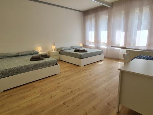 two beds in a room with wooden floors and windows at Infinity Collection in Padova