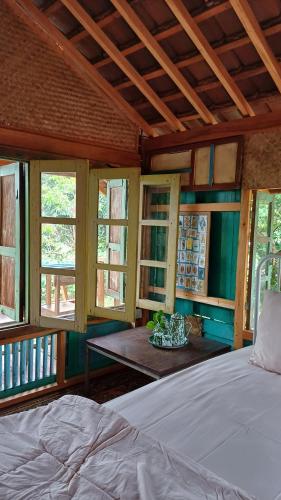 a bedroom with a bed and a table with windows at Omah Kepel Yogyakarta in Soprayan