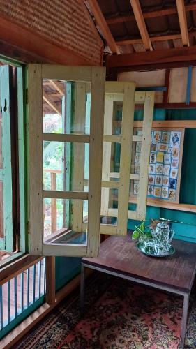 a room with a wooden table and two windows at Omah Kepel Yogyakarta in Soprayan