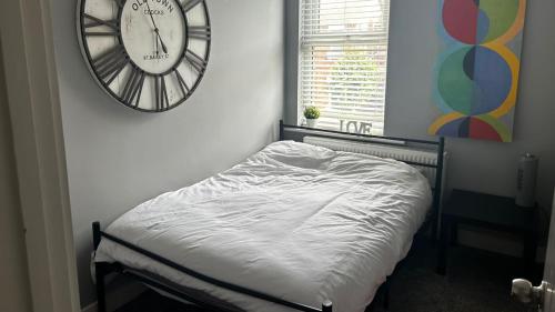 Sleep up to 14 - Doncaster central في دونكاستير: غرفة نوم بسرير وساعة على الحائط
