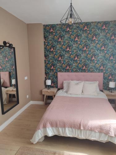 1 dormitorio con cama rosa y pared de flores en DIVINA GUEST HOUSE, en Manzanares