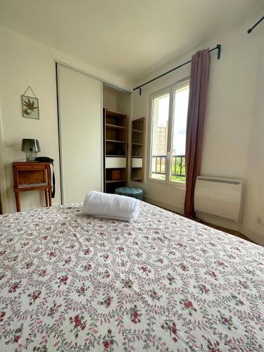 une chambre avec un lit avec un couvre-lit fleuri dans l'établissement Le doux refuge à 5mn Paris & 10mn Stade de France, à Saint-Ouen