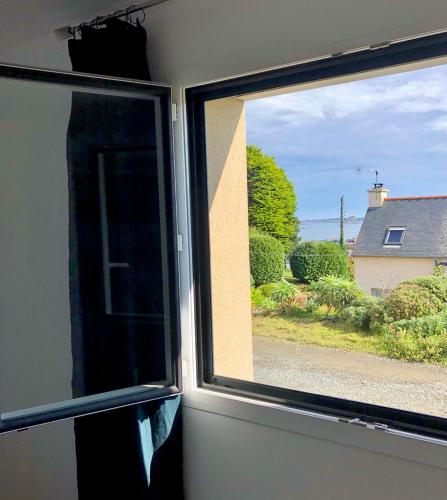 a window with a view of a house at Les chambres du Roc'h Hir à Loguivy de la Mer in Ploubazlanec
