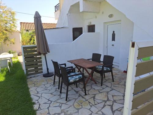 eine Terrasse mit einem Tisch, Stühlen und einem Sonnenschirm in der Unterkunft Foivos Seaside Apartments in Agios Georgios