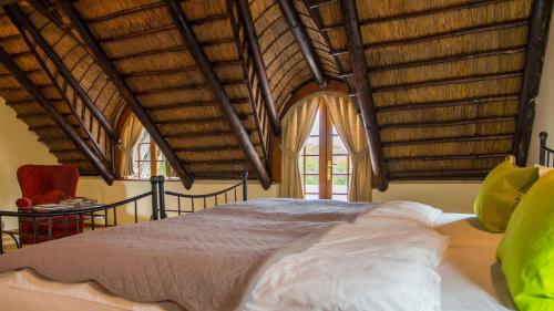 a bedroom with a bed with wooden ceilings and windows at Klein Paradijs Country Retreat in Pearly Beach