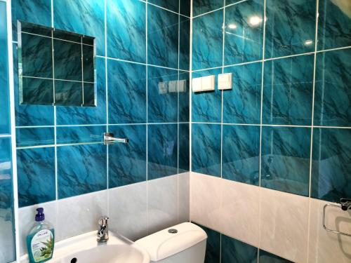 a blue tiled bathroom with a sink and a toilet at Gościniec u Zawierki in Łódź