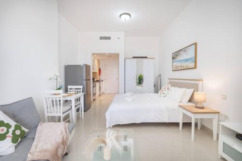 a white bedroom with a bed and a kitchen at Serene Studio & Sea View & Brand New Listing in Ras al Khaimah