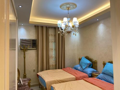 a bedroom with two beds and a chandelier at LuXury Apartment Agouza-Mohandesin in Cairo
