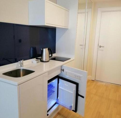 a small white kitchen with a sink and a dishwasher at Orbi hotel sea view in Kuwait