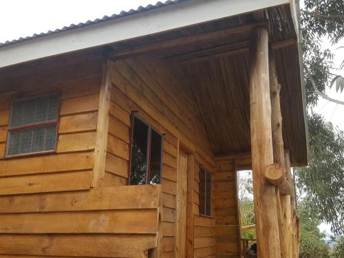 Cabaña de madera con porche y ventana en Eagle Peak homestay en Kabale