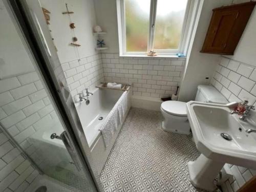 a bathroom with a tub and a toilet and a sink at Rhianfa 4 bedroom house minutes walk from the beach in New Quay