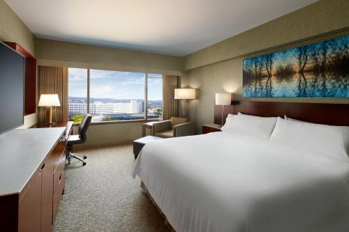 a hotel room with a large white bed and a desk at The Westin San Francisco Airport in Millbrae