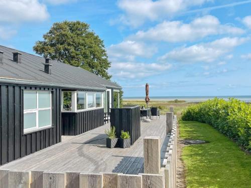una casa con terraza de madera junto al océano en 6 person holiday home in Hadsund, en Haslevgårde