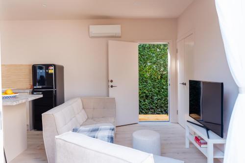 a living room with a white couch and a television at Heights Guesthouse - Hideaway in Kiama Heights in Kiama