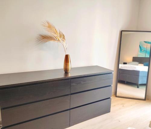 a dresser with a vase on it with a mirror at Design Apartment Vienna City Center - free parking! in Vienna